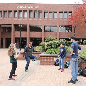 学生们在九五至尊官方网站主校区的比灵顿图书馆外玩曲棍球.