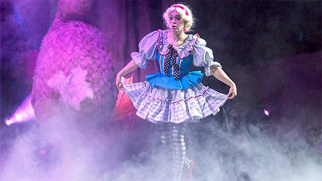 扮演爱丽丝的女演员伸出裙子在舞台上穿过雾