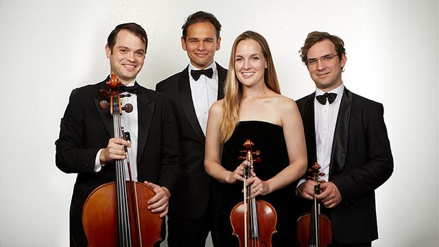 “Opus 76”乐队的4名成员系着黑色领带，手拿乐器，对着镜头微笑